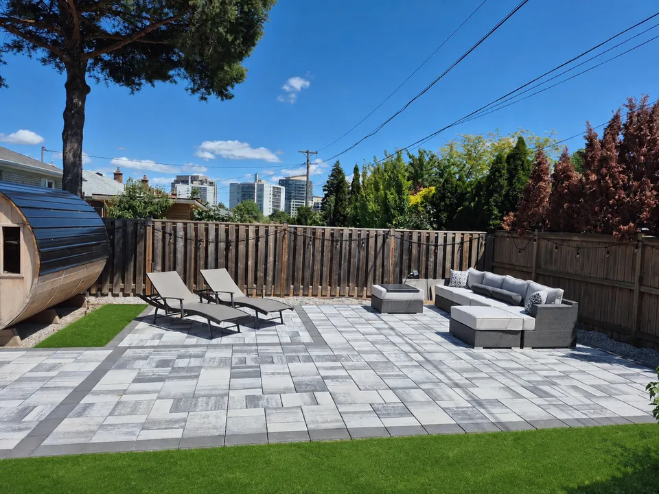 Completed interlock seating area with grey pavers and dark borders; grass digitally added to illustrate the surrounding lawn.