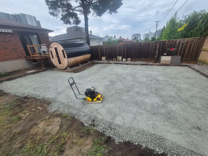 Aggregate base preparation and compaction in the backyard before paving.