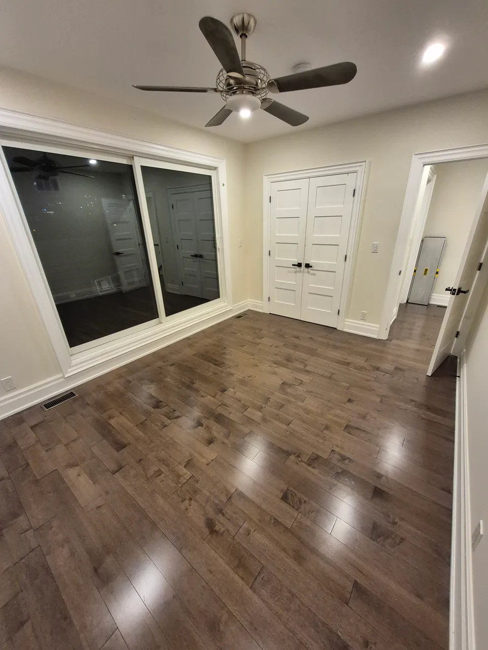 Bedroom following painting, with a ceiling fan, large window and existing timber floor.