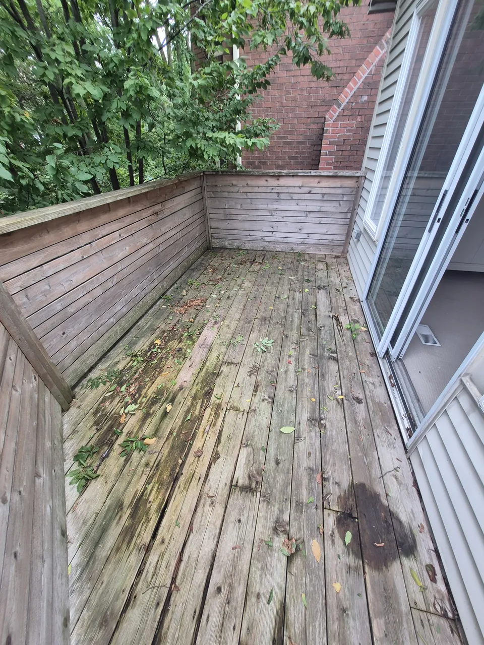 Weathered upper deck boards and the original solid-board railing beside the house.